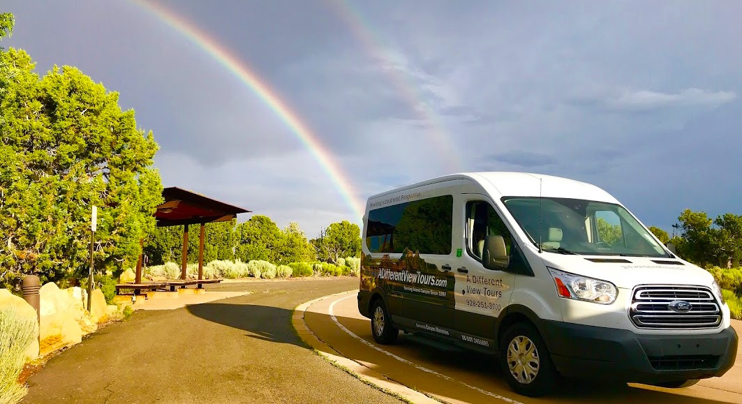Canyon Ministries tour van beneath a rainbow at Desert View