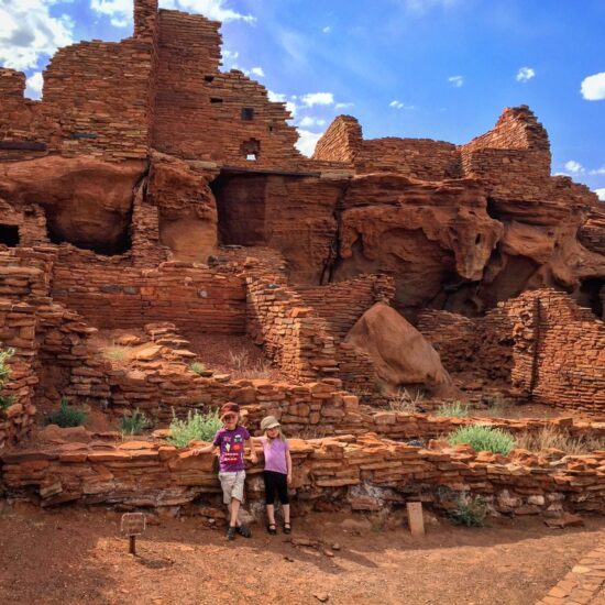 The children gaze at the historic site with awe, their imaginations running wild with stories of the past inhabitants. One points towards a distant petroglyph, while the other holds a guidebook that describes the former communitys way of life. Together, they venture onward to explore more of Wupatkis secrets.